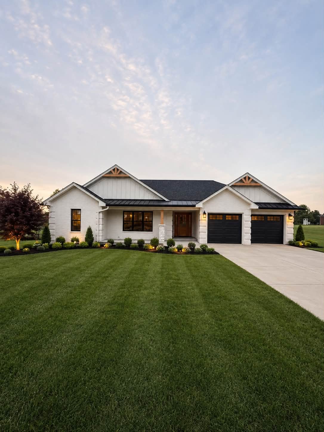 A finished new-build home exterior photographed at dusk, windows lit from inside.